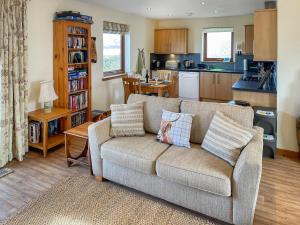 a living room with a couch and a kitchen at The Barn in Lairg