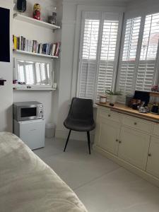 a bedroom with a chair and a desk with a microwave at Rose in Croydon