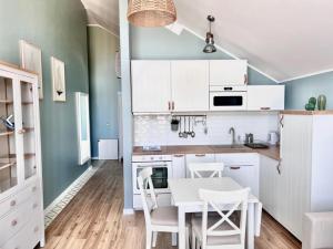 a kitchen with white cabinets and a table and chairs at Apartament Łeba Piaskowa Ostoja in Żarnowska +3 photos