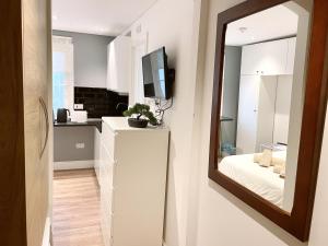 a white kitchen with a mirror and a bed at Stylish City Centre Studio - Grand Central House in Gibraltar