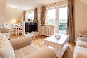 a living room with a couch and a tv at White House Ferienwohnung 2 in Alkersum