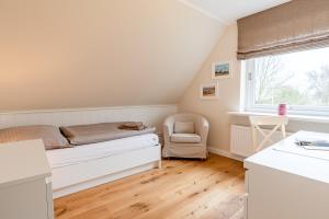 a bedroom with a bed and a chair and a window at White House Ferienwohnung 2 in Alkersum