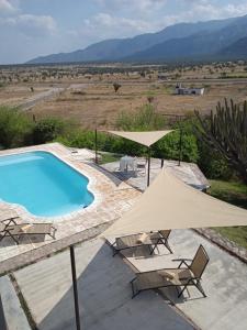 ein Pool mit zwei Stühlen und Sonnenschirmen daneben in der Unterkunft QHAWANA CABAÑAS & SUITES in La Rioja