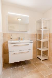 a bathroom with a white sink and a shelf at White House Ferienwohnung 1 in Alkersum