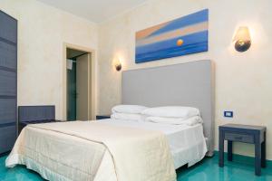 una camera da letto con letto, lenzuola e cuscini bianchi di AH Premium Baia dei Faraglioni a Mattinata
