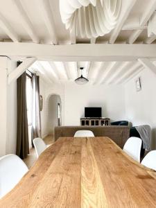 - une table en bois dans le salon avec des chaises blanches dans l'établissement Maison de Ville Rénovée avec Charme, à Pont-Sainte-Maxence