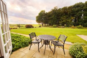 einen Tisch und Stühle auf einer Terrasse mit Rasen in der Unterkunft Heacham Manor Hotel in Hunstanton