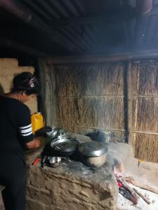 una mujer parada sobre una estufa con ollas y sartenes en Nanu's Bardiya Homestay, en Bhurkīā