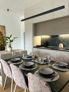 a dining table with chairs and plates and wine glasses at Apartment Llama in Trebinje