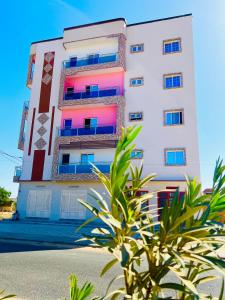 a tall white building with colorful windows and a plant at Résidence Mounir in Thiès