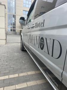 een zilveren busje geparkeerd op een stoep naast een gebouw bij Diamond Hotel in Chişinău