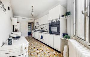 cocina con armarios blancos y suelo de baldosa en 3 Bedroom Pet Friendly Apartment In Issy-lvque en Issy-lʼÉvêque