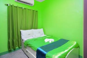Golden V Executive Homes Unit H في Malolos: غرفة نوم خضراء مع سرير عليه كلب ابيض