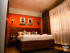 Enkipai Hill Hotel في Narok: غرفة نوم بسرير بحائط برتقالي