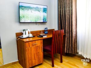 a wooden desk with a chair and a television on a wall at Enkipai Hill Hotel in Narok