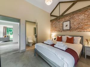 una camera con un grande letto con un muro di mattoni di Partridge a East Ilsley