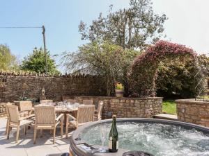 a patio with a table and chairs and a hot tub at Nempnett Farmhouse in Bristol