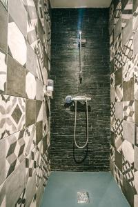 a bathroom with a shower with a tile wall at Le Dôme et son jacuzzi in Grazac