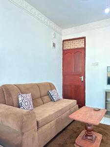 a living room with a brown couch and a red door at Rainbow apartment in Mombasa