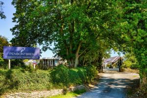 a sign in front of a road with a tree at Penbontbren Luxury Bed and Breakfast in Aberporth