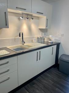 a kitchen with white cabinets and a sink at The Home Away From Home in Great Harwood