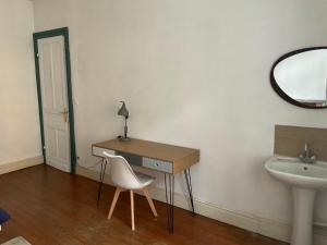 ein Badezimmer mit einem Schreibtisch mit einem Stuhl und einem Waschbecken in der Unterkunft Ancienne maison de maitre in Douai