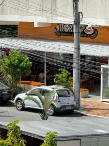 un coche blanco estacionado frente a un restaurante en Suítes Viver Arraial do Cabo, en Arraial do Cabo