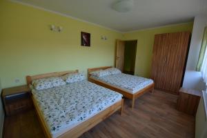 two beds in a room with yellow walls and wooden floors at Domyletnie Sarbinowo 8e dom 86m2 z ogrodzoną działką in Sarbinowo