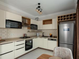 a kitchen with white cabinets and a stainless steel refrigerator at VİLLA BLUE CRAB in Ortaca