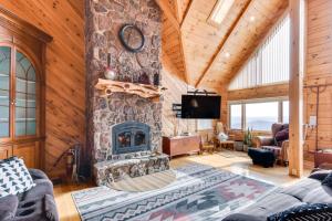 a living room with a stone fireplace and a tv at Spacious Howard Cabin with Wraparound Deck and Views! 
