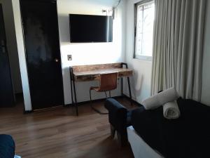 a room with a desk and a bed and a television at Santa María Express in Santiago