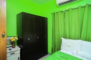 ein grünes Schlafzimmer mit einem Bett und einem schwarzen Schrank in der Unterkunft Golden V Executive Homes Unit I in Malolos