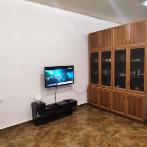 sala de estar con TV de pantalla plana y armarios de madera. en LANJ IN Eco Garden/ Guest House, en Nurrnus