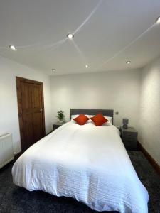 a bedroom with a large white bed with red pillows at The Home Away From Home in Great Harwood