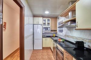 eine Küche mit weißen Geräten und Holzschränken in der Unterkunft BBarcelona Gaudí Avenue Flat in Barcelona