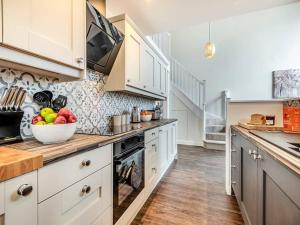 a kitchen with white cabinets and a bowl of fruit on the counter at Pearmain in Spilsby