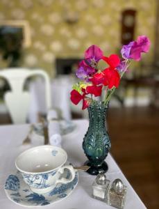 a vase of flowers and a cup on a table at Penbontbren Luxury Bed and Breakfast in Aberporth