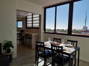 comedor con mesa, sillas y ventanas grandes en Beach Apartment w/Ocean view en Costa da Caparica