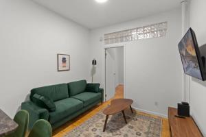 ein Wohnzimmer mit einem grünen Sofa und einem Tisch in der Unterkunft Cozy 1BR in the Upper East Side in New York