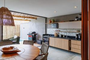 a kitchen with a wooden table and a dining room at Pysá Zero Um in São Miguel dos Milagres