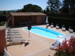 einen Pool mit Liegestühlen und einem Sonnenschirm in der Unterkunft VILLA AVEC PISCINE in Roussillon