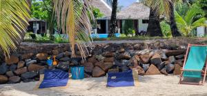 a beach with two chairs and a pile of rocks at La Villa Boraha Location de villa entière en bord de plage Piscine privée Wifi Ile Sainte Marie in Sainte Marie