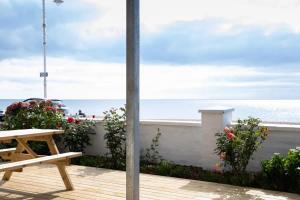 a wooden deck with a bench and a view of the ocean at Absolute Beachfront with Decked Garden Oasis and Views in Bognor Regis