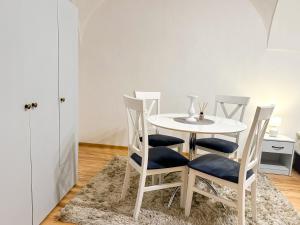 mesa de comedor blanca con 4 sillas y alfombra en Old Town apt. A/C and parking, en Banská Bystrica