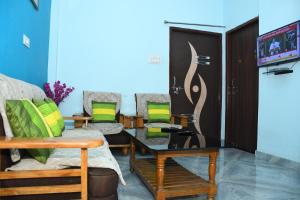 uma sala de estar com sofás e uma televisão e uma televisão em Indra Apartment em Varanasi