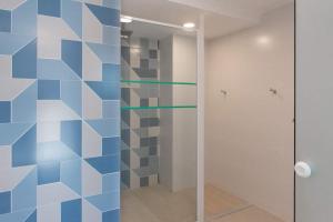 a bathroom with a shower with blue and white tiles at Leblon Inn, Ótimo Ap in Rio de Janeiro