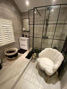 a bathroom with a white chair and a shower at Beautiful Period Victorian Home Quirky & Charming in Handforth