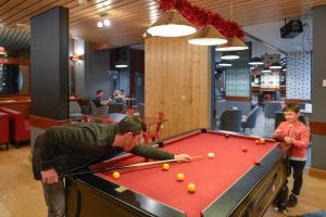 a man playing pool with a young boy at Villages Clubs du Soleil - LES KARELLIS in Montricher-Albanne