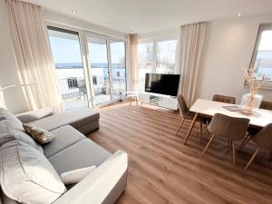 uma sala de estar com um sofá e uma mesa em Seeliebe Apartments Schwerin - am See, Seeblick, PKW, Sauna, XXL-Balkon, Terrasse, modern em Schwerin