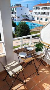 a patio table and chairs on a balcony with a pool at Apartamento junto a la playa con terraza y piscina in Cala en Blanes